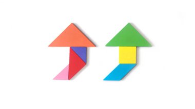 Ayrı bir el, beyaz arka planda ok şeklinde renkli tangram yapbozu tutuyor. Bulmaca konsepti. İlerleme, sonraki adım, büyüme kavramı