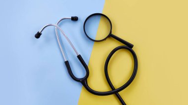 Stetoskop ve sarı arka planda büyüteç ile hastalıkların teşhisi. Sağlık, teşhis, araştırma ve tıbbi planlama konuları için mükemmel.