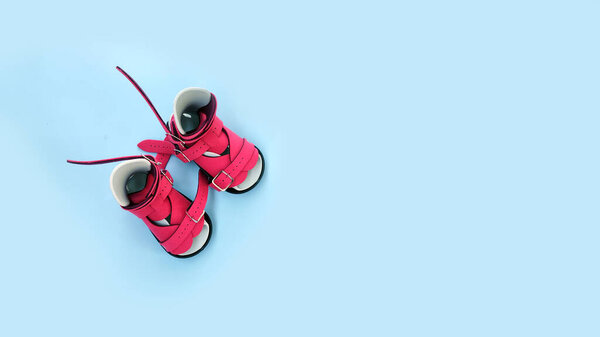 Pair of pink orthopedic boots for infant clubfoot treatment placed on blue background, symbolizing pediatric care and correction.