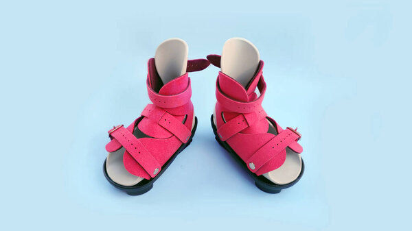 Front view of pink orthopedic boots designed for infant clubfoot correction, isolated on blue background.