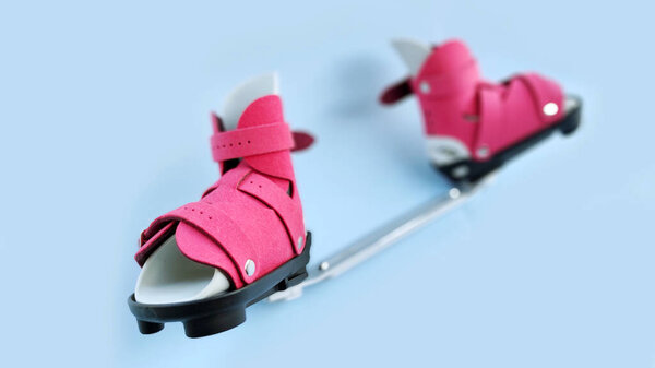Perspective view of orthopedic boots connected by bar brace, representing pediatric clubfoot treatment and correction system.