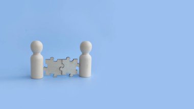 İş ortaklığı, anlaşma ve işbirliğini temsil eden yapboz parçalarıyla birbirine bağlı iki tahta figür..