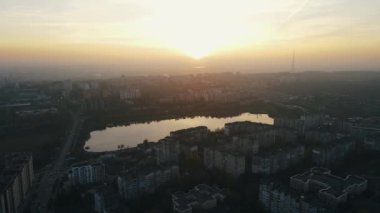 Gün batımında çok katlı binalar, parklar ve nehirler olan sakin bir yerleşim yeri.