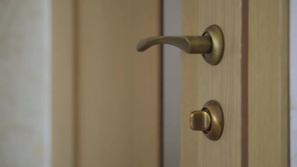 Kobieta otwiera drzwi za klamką i wychodzi z pokoju w domu. — Wideo stockowe