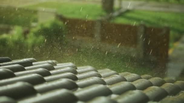 Fuertes lluvias de verano caen en el techo de una casa en un día soleado — Vídeos de Stock