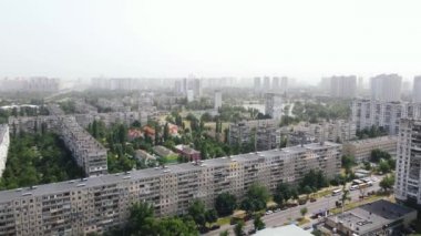 Çevresinde yeşil ağaçlar ve arka planda gökdelenler olan yerleşim alanları.