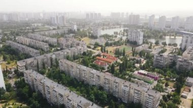 Çevresinde yeşil ağaçlar ve arka planda gökdelenler olan yerleşim alanları.