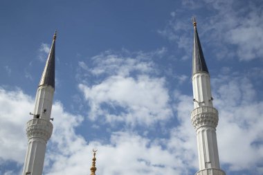 İki uzun beyaz cami minaresi, dağınık bulutlarla mavi gökyüzüne yükseliyor. İslami mimarinin, ruhaniliğin ve inancın sembolü. Seyahat, din ve kültür kavramları için mükemmel..