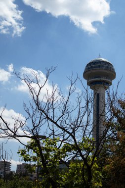 03.09.2025, Ankara, Türkiye Atakule kulesinin tepesi, arka planda bulutlar bulunan yapraksız dalların arkasında beliriyor. Çerçeve yapısı ve yüksekliği vurgular. Ufuk çizgisi ve kentsel doğa üzerindeki özellikler için uygun; 