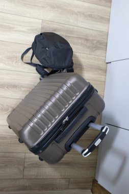 Genişletilmiş kulplu küçük bir bavul ve otellere yerleştirilmiş siyah bir sırt çantası listeler için ahşap zemin görselleri, seyahat planlama ya da taşınma harçlıkları