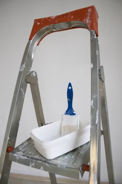 Boya tepsisiyle metal merdiven ve çalışma platformunda duvarın yeniden boyanması ve yenilenmesi için hazırlanmış parlak bir oda..