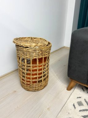 Ev deposu olarak kullanılan kapalı doğal hasır sepet, ahşap zeminde duruyor, minimalist iç kısımda sıcak nötr tonlar var..