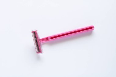 Temiz, parlak beyaz bir arka plana yerleştirilmiş tırtıklı pembe bir jilet. Bu madde bakım ve hijyen ürünlerini temsil ediyor.