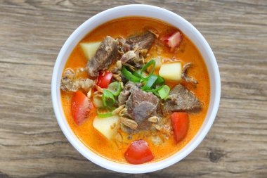 Bir kase Soto Betawi, taze sığır eti, domates, patates parçaları ve taze soğanla süslenmiş kalın, kremalı bir çorba karışımını vurguluyor..