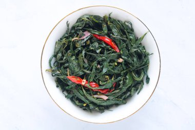 Bir tabak Daun Singkong, geleneksel Endonezya baharatlı kaju yaprağı, garnitür olarak kırmızı biber ile servis edilir..