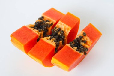 Beyaz arka planda taze kesilmiş üç papaya dilimi canlı portakal eti ve siyah tohumları vurguluyor..
