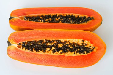 Taze bir papaya beyaz arka planda yarı yarıya dilimlenmiş, canlı portakal eti ve siyah tohumları ortaya çıkarıyor..