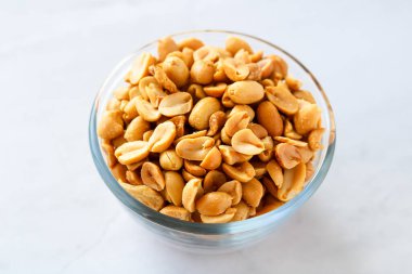 Fırında pişmiş fıstıklarla dolu cam bir kase. Koyu kahverengi rengini ve kavrulmuş dokusunu vurguluyor..