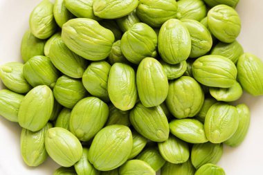 Taze petai ya da Pete 'e yakın çekim. Beyaz tabakta kokuşmuş fasulye olarak da bilinir..