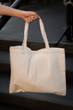 Bir kişi, günlük kullanım için pratik ve yeniden kullanılabilir bir aksesuar sergileyen beyaz bir çantasıyla dışarıda duruyor. Portre sürümü.