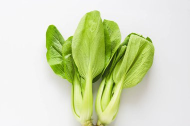 Parlak yeşil yaprakları ve sapları olan iki taze bok çuvalı, temiz beyaz bir arka planda dizilmiş..
