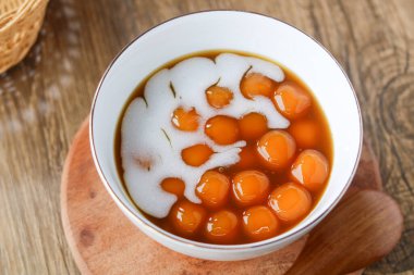 Bir kase Endonezya Biji Salak (Palm Sugar Sosu 'nda Tatlı Patates ve Tapioca Balls) yakından görülüyor. Ahşap bir arka planda doğal ışıkla yakalanmış..