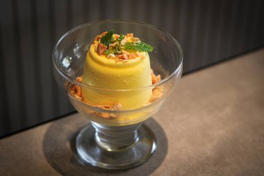 Berrak bir cam kadehte servis edilen durian aromalı ferahlatıcı ve kremalı bir dondurma. Tatlı bir tutam fındık ve taze nane yaprağıyla süslenir..