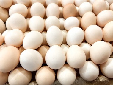 Soluk kahverengi ve beyaz tavuk yumurtalarının yukarıdan görünüşü doğal ve kümelenmiş bir şekilde düzenlenmiştir. Yumurtalar, taze ve organik kalitelerini vurgulayarak renk ve dokuda ince varyasyonlar sergiler..