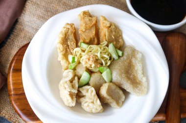 Bir tabak dolusu Pempek (veya Empek-Empek), Palembang 'tan geleneksel bir Endonezya balık keki tabağı, erişte ve dilimlenmiş salatalıkla birlikte yığılmıştır. Bir kase koyu Cuko sosu da görülebilir..