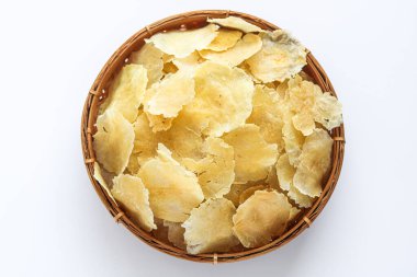 Kahverengi sepetin içinde bir yığın çiğ, pişmemiş Boş Melinjo (Melinjo Fındık Krakeri). Bunlar geleneksel Endonezya atıştırmalıkları, kurutulmuş ve kraker olmak için kızartılmaya hazır..