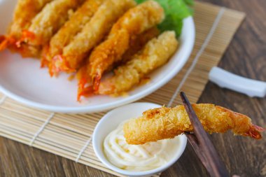 Kızarmış karidesi (Ebi Fry veya Tempura) sosa batırmak için çubuk kullanmak.