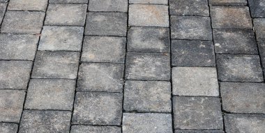 Dikdörtgen gri ve siyah kaldırım taşları ya da kaldırımlarla döşenmiş bir avlunun tam kare, yüksek açılı dokusu.