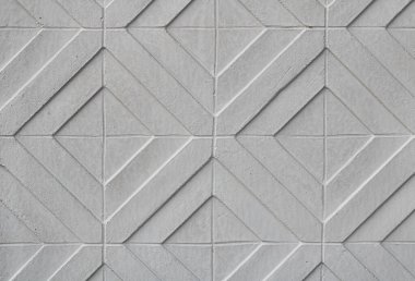 Açık gri, beyaz beton ya da taştan yapılmış geometrik duvar desenli bir panelin tam kare, pürüzsüz dokusu. Çapraz çizgileri ve elmas şekilleri olan modern beton ya da taş fayanslara yakın çekim.