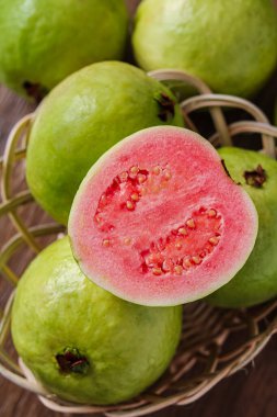 Yeşil guava meyvesinin portre görüntüsü, canlı pembe bir iç mekan ortaya koyan yarım yamalak bir parça içeriyor..