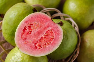 Yeşil guava meyvesinin tamamının yakın plan çekimi, canlı pembe bir iç mekan içeriyor..