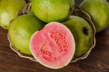 Yeşil guava meyvesinden oluşan bir düzenleme. İçinde canlı pembe bir iç mekan olan yarım bir parça var..