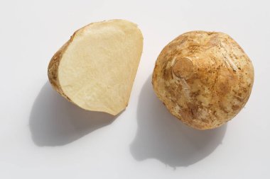Bütün bir Bengkuang (Jicama) dilimlenmiş yarısının yanında, sert, kahverengi deriyi sergiliyor. Bu sebze, salata ve meyve hazırlıklarında sıkça çiğ yenir..