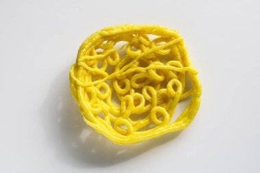 Kerupuk Mie Keriting 'in bir parçası ya da beyaz arka planda izole edilmiş kıvırcık sarı erişte krakeri..