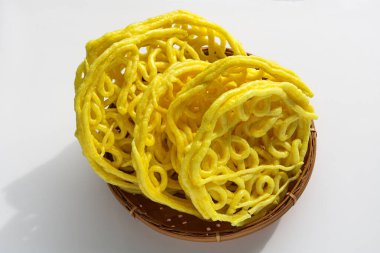 Bir porsiyon Kerupuk Mie Keriting, ya da kıvırcık sarı erişte krakerleri, geleneksel dokuma sepetinde üst üste yığılmış..