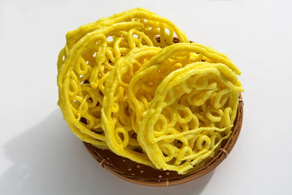Bir porsiyon Kerupuk Mie Keriting, ya da kıvırcık sarı erişte krakerleri, geleneksel dokuma sepetinde üst üste yığılmış..