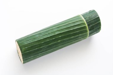 Tüm tempeh geleneksel muz yaprağına sarılmış, temiz beyaz bir arka planda sergileniyor..