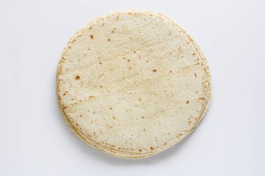 Temiz beyaz arkaplana yerleştirilmiş tortilla ambalajlarının üst görünümü, yumuşak dokularını ve ışıklarını vurguluyor, benekli yüzey.