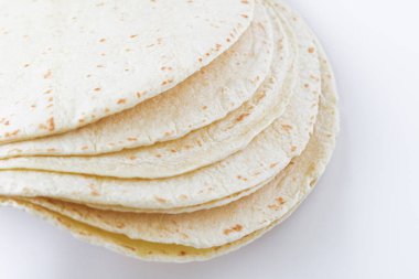Temiz beyaz arkaplana yerleştirilmiş tortilla ambalajlarının yakın görüntüsü, yumuşak dokularını ve ışıklarını vurguluyor, benekli yüzey.