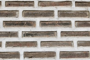 Kahverengi tuğla duvarın tam kare arka planı tuğlaların pürüzlü, gözenekli dokusunu ve zıt beyaz harcı gözler önüne seriyor..