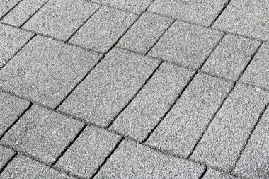 Birbirine kenetlenmiş gri beton kaldırım bloklarının perspektif çekimi. Bu dayanıklı ve temiz asfalt döşeme kentsel peyzaj ve açık hava yürüyüşü tasarımında yaygındır..