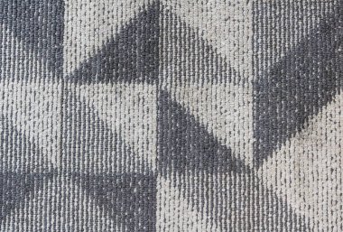 Keskin geometrik üçgen desenli kalın, dokumalı bir tekstilin tepeden tırnağa yakın çekimi. Yüksek kontrastlı kömür grisi ve krem rengi ağır, dayanıklı lif dokusunu vurgular.