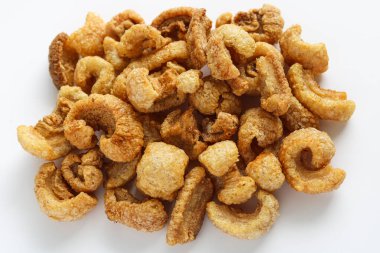 Temiz beyaz arka planda kıtır kıtır kızarmış domuz derisi. Bu gevrek, havadar domuz derileri popüler ve lezzetli bir atıştırmalık..