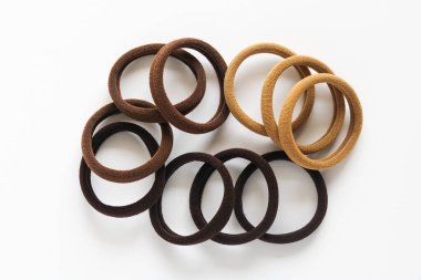 Bir demet elastik, kumaş kaplı saç teli, beyaz arka plana yaslanmış, günlük aksesuarın basit dokusunu gösteriyor..