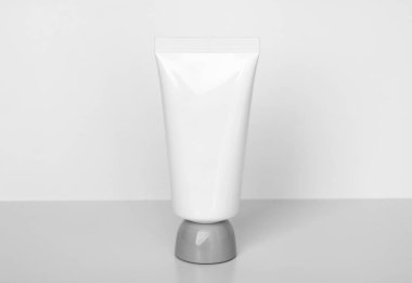 Temiz, minimalist kozmetik tüp modellemesi beyaz, hafif gri bir zeminde, açık bir arkaplanda duruyor. El kremi, losyon, yüz yıkama veya diğer ürünler için ideal..