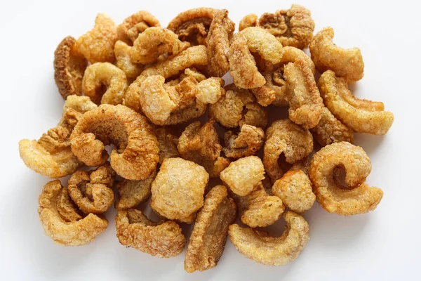 Temiz beyaz arka planda kıtır kıtır kızarmış domuz derisi. Bu gevrek, havadar domuz derileri popüler ve lezzetli bir atıştırmalık..